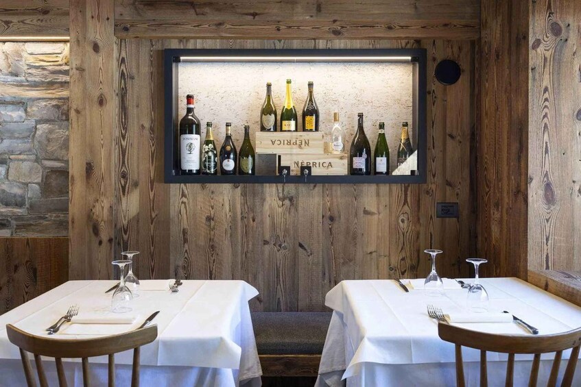 A rustic wooden interior with a wine display and two tables set for dining. 3