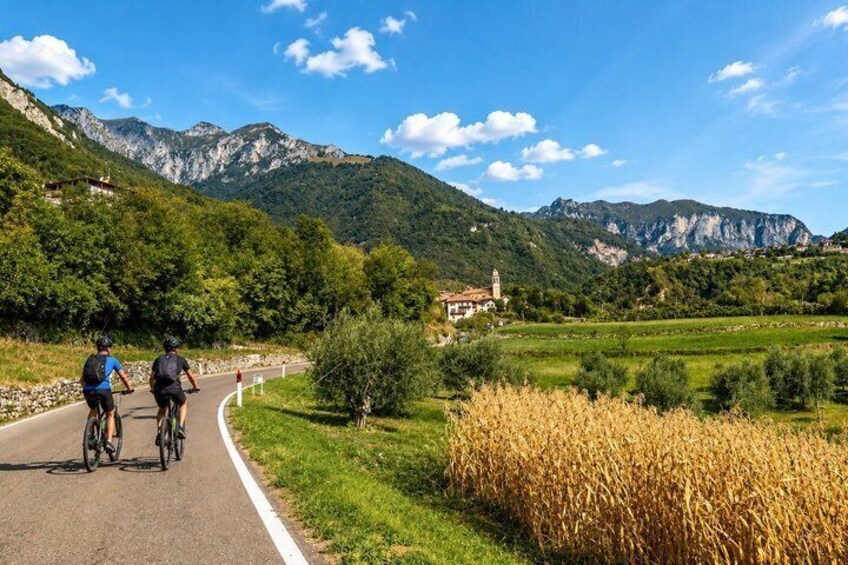 A road with cyclists, a mountain landscape, and a building in the distance. 2