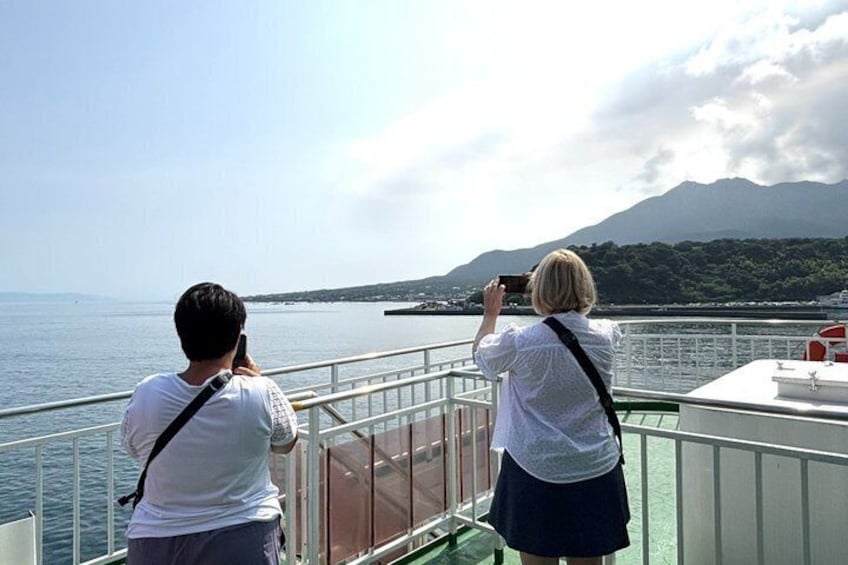Two people taking photos of a mountainous landscape from a boat. 2