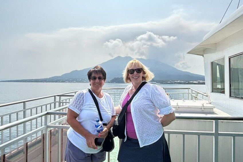 Two people standing on a boat deck with a mountainous landscape in the background. 3