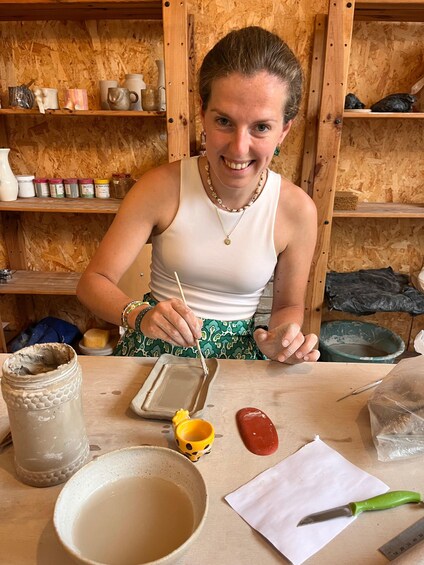 A person painting a ceramic mug with a brush. 3