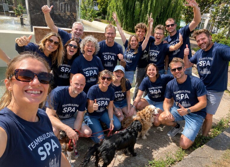 A group of people wearing 'Teambuilding SPA' t-shirts gathered outdoors, some holding dogs. 4