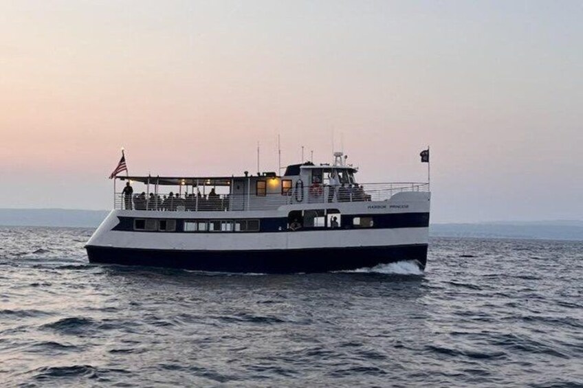 A large ferry boat with a white and black color scheme, moving on calm waters during sunset. 2