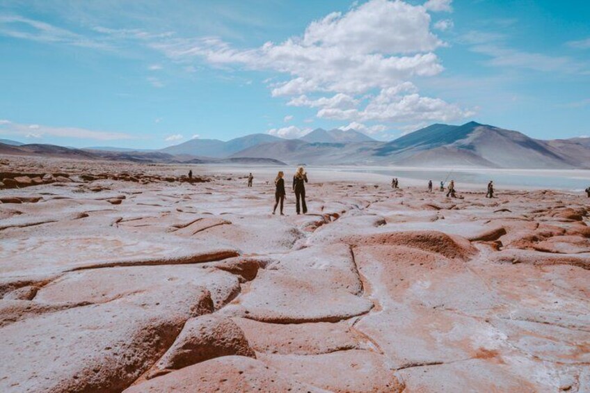 A barren landscape with a group of people standing in the distance, a clear sky, and distant mountains. 5