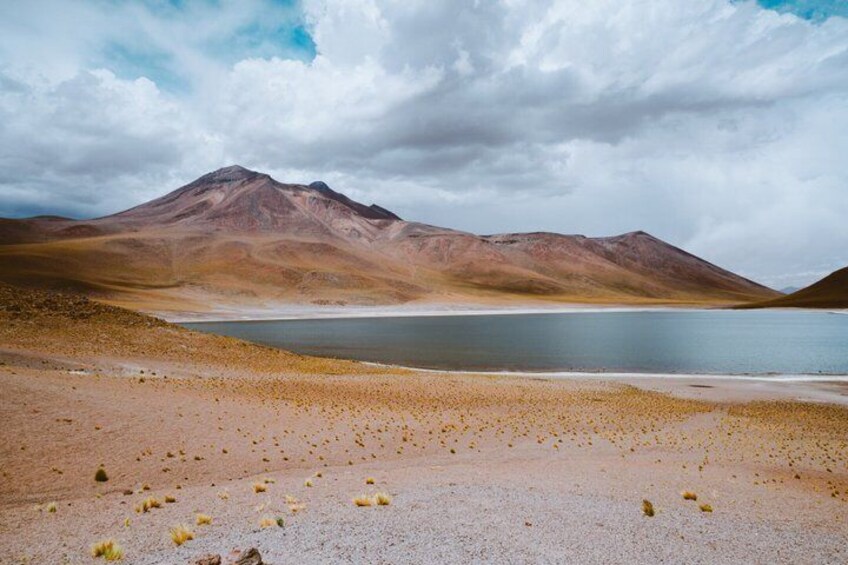 A desert landscape with a lake and mountains. 3