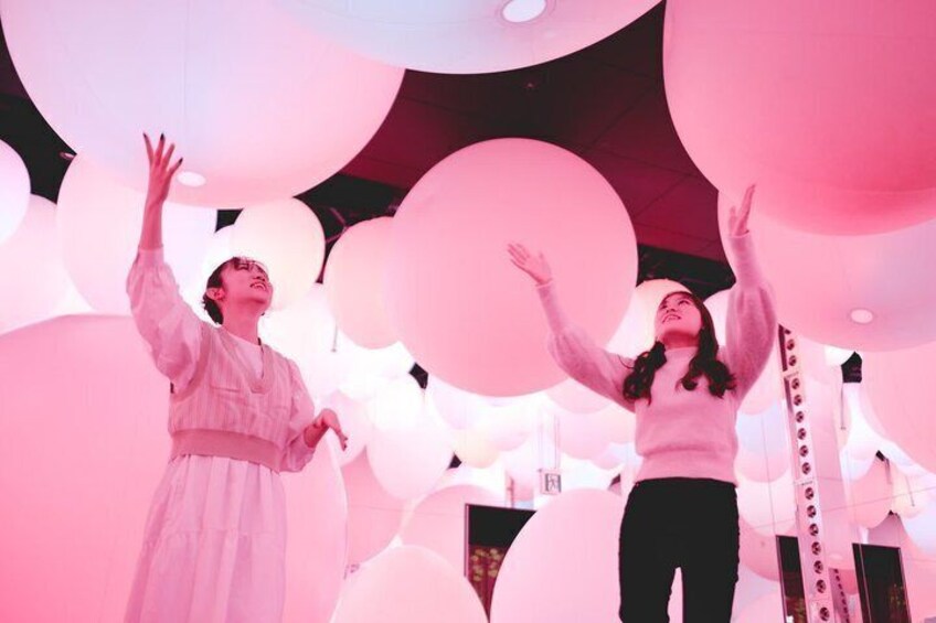 Two people in a room with large pink balloons. 4