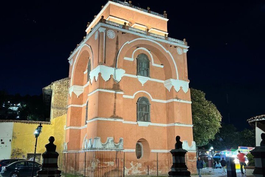 A historic building with arched windows and a clock tower at night. 1