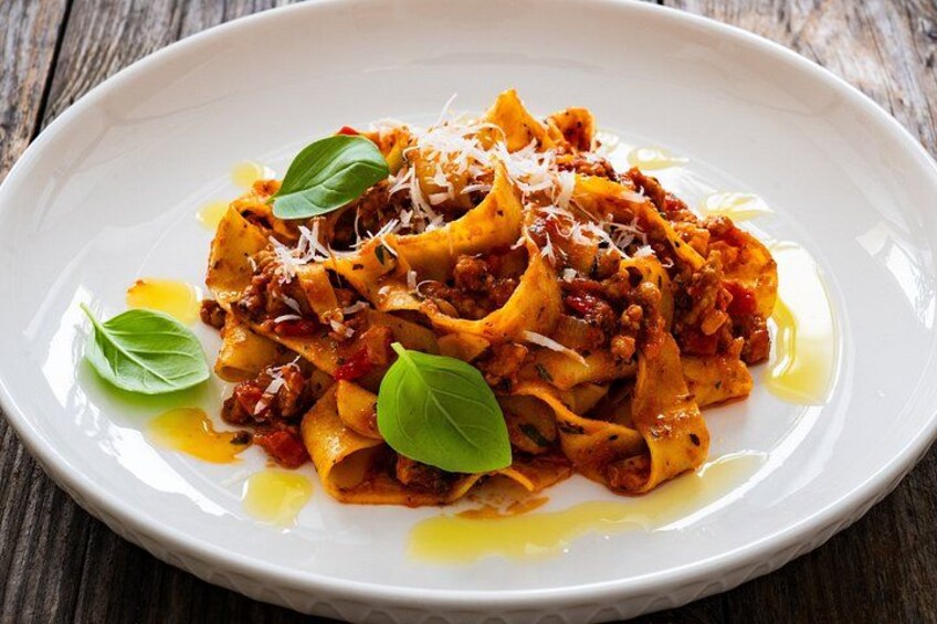 A plate of pasta with a tomato-based sauce, garnished with basil leaves and grated cheese. 3