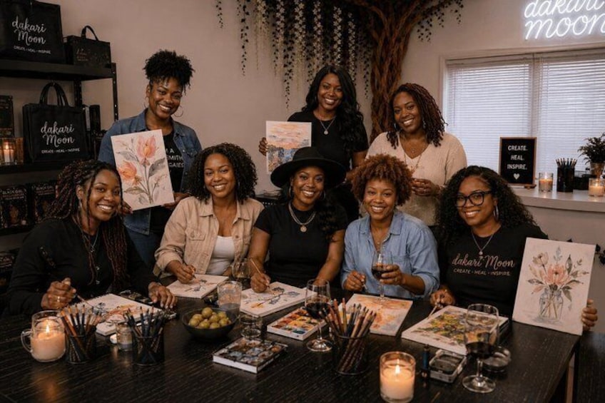A group of people at a table with art supplies, books, and candles. 1