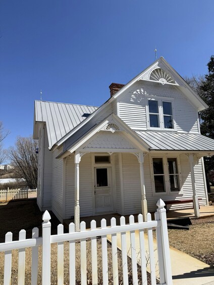 A white house with a gabled roof and a white picket fence. 2