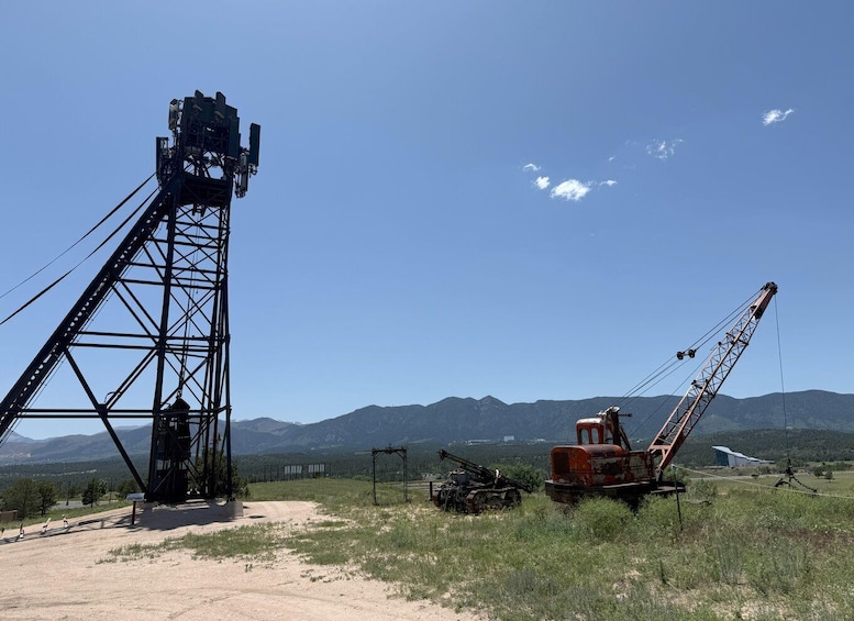 A metal tower, a red excavator, and a mountainous landscape under a clear sky. 3
