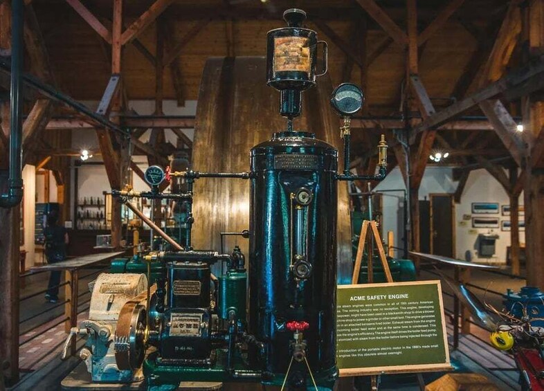An ACME Safety Engine in a wooden building with visible pipes and gauges. 1