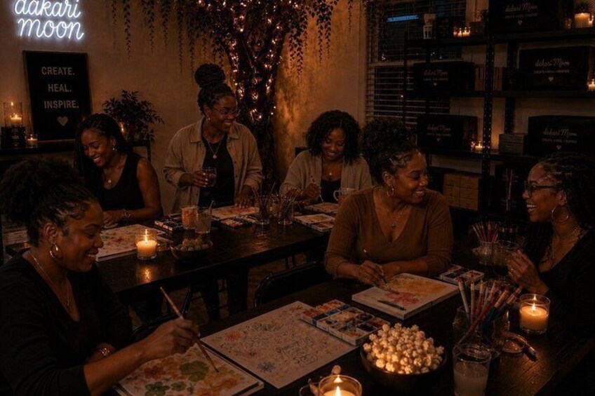 A group of people sitting around a table with candles, books, and snacks. 1