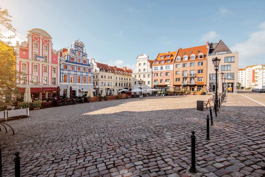 A cobblestone square with historic buildings, outdoor cafes, and a clear sky. 2