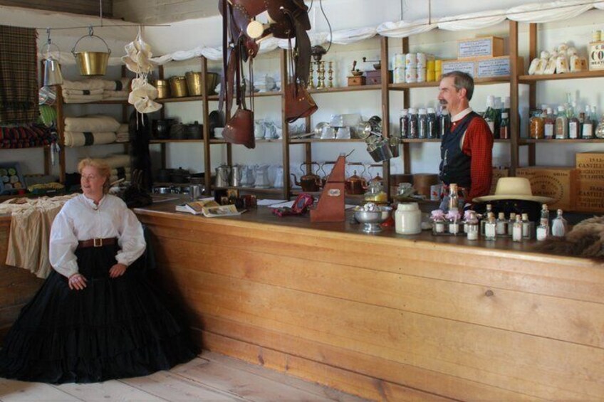 A vintage shop interior with wooden shelves, hanging items, and a counter. 5