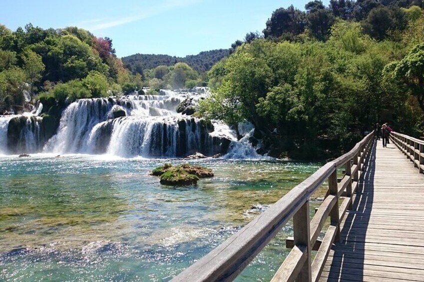 A wooden bridge over a river with a waterfall. 4