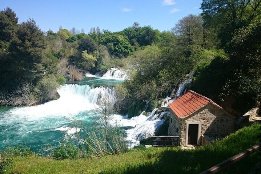 A waterfall, a stone building, and lush greenery. 5