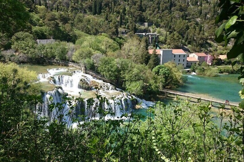 A waterfall cascading into a river surrounded by greenery and buildings. 3