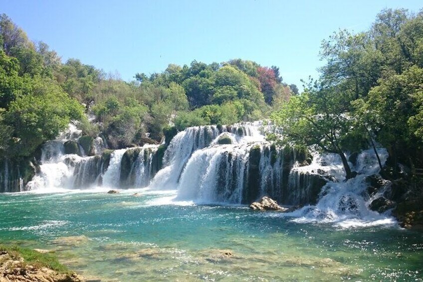 A multi-tiered waterfall surrounded by lush greenery. 1