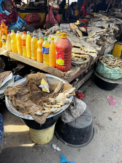 A market stall with various goods including bottled drinks, dried fish, and sacks of grains. 3