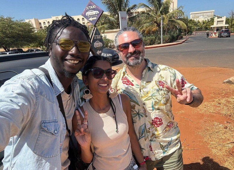Three people posing for a photo, a taxi sign, and a building in the background. 1