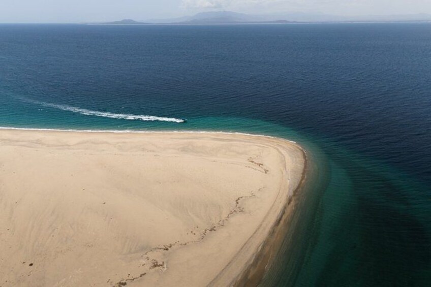A coastal landscape with a sandy beach and a clear blue ocean. 2