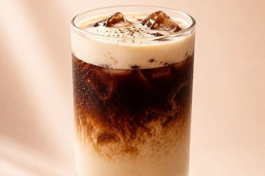 A glass of iced coffee with a layer of milk foam on top. 2
