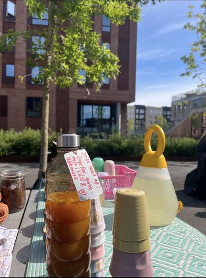A table with various bottles and containers, a yellow funnel, and a handwritten note. 1