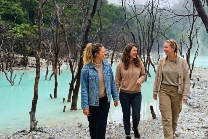 Three people walking along a beach with trees in the background. 1