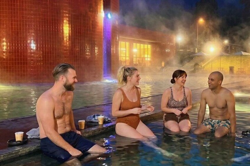 A group of people sitting by a heated pool at night. 4