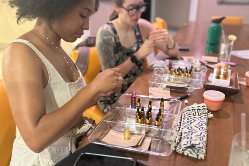 A group of people engaged in a makeup application activity at a table with various cosmetic products and tools. 4