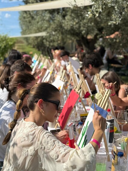 A group of people engaged in painting at an outdoor event. 1