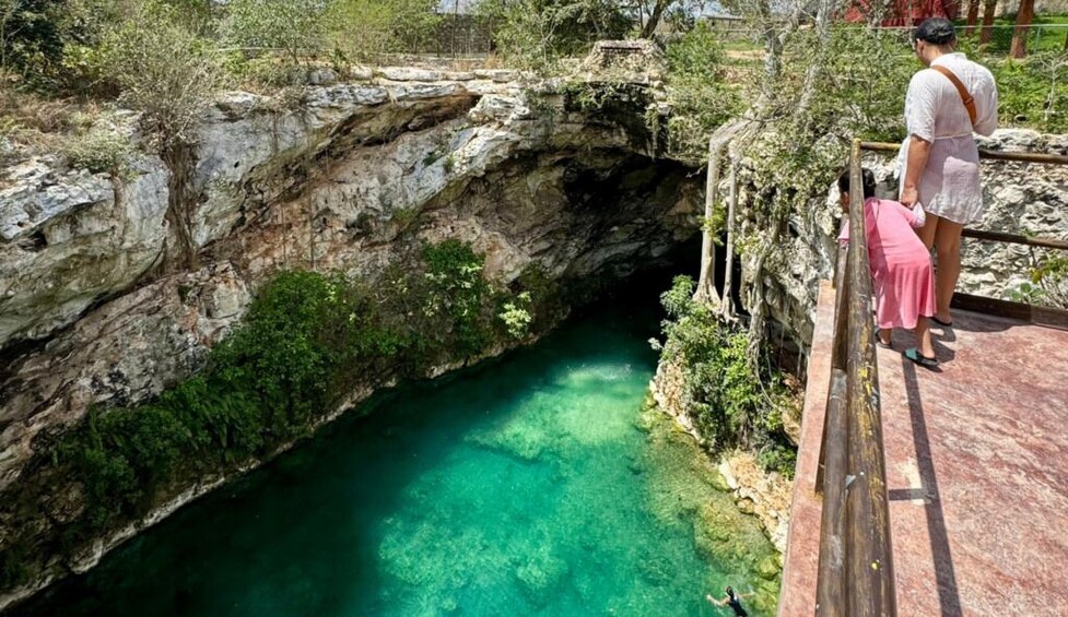 Eine natürliche Höhle mit klarem, türkisblauem Wasser, umgeben von Grünpflanzen und steinernen Wänden. 2