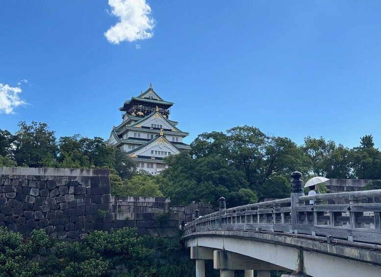 A traditional Japanese castle with a stone wall and a bridge in the foreground. 1