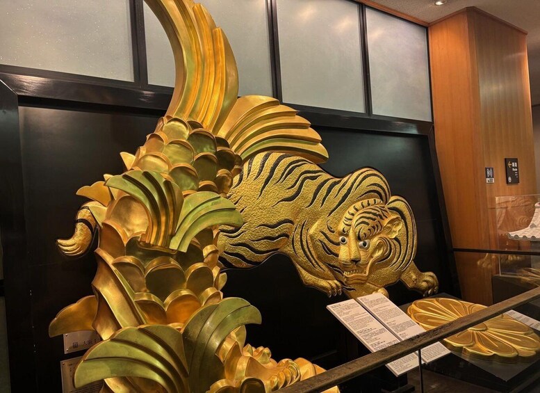 A golden tiger sculpture with intricate details and a display case with informational placards. 2