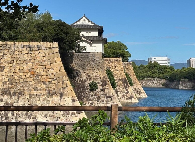 A traditional Japanese castle with a stone wall and a wooden fence in the foreground. 3