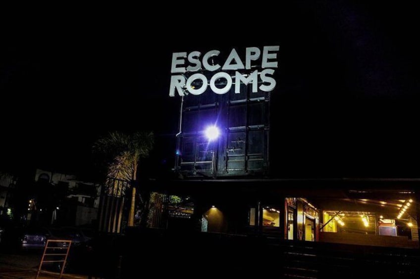 A building with a sign that reads 'ESCAPE ROOMS' at night. 3