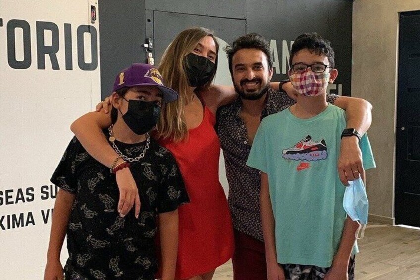 A group of people standing indoors with a wall that has text and a door in the background. 2