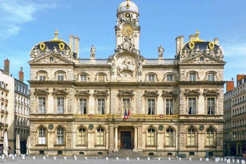A historic building with a clock tower, arched windows, and statues. 5