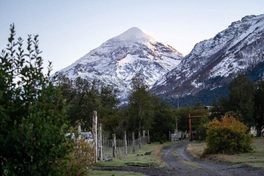A snow-covered mountain, a dirt path, and a fence. 2