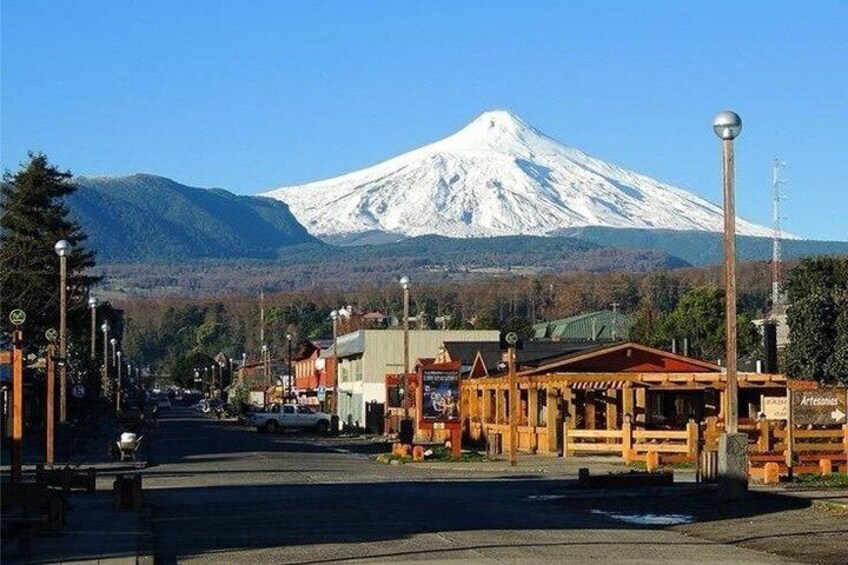 A town street with buildings, a wooden structure, and a snow-capped mountain in the background. 1