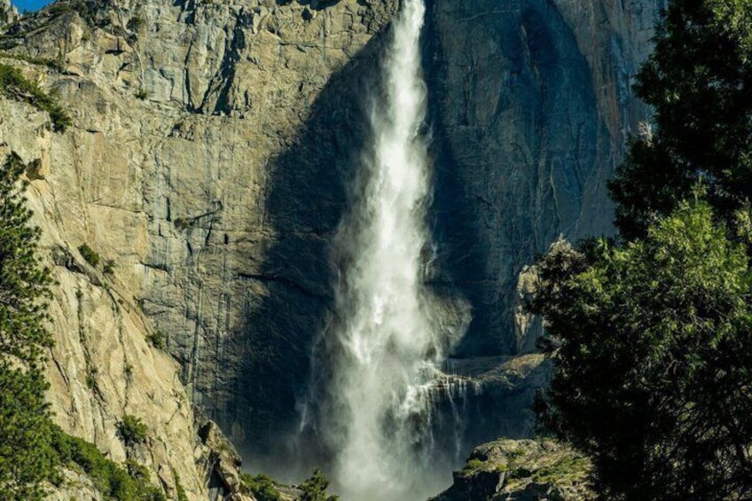 A waterfall cascading down a rocky cliff surrounded by trees. 1