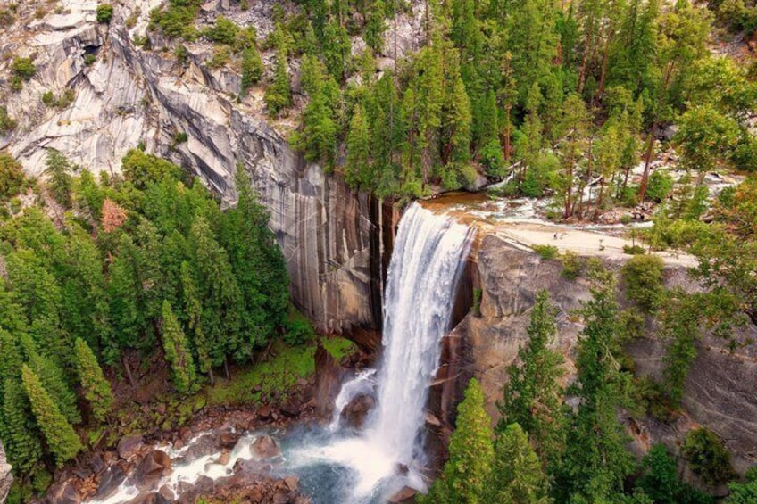 A waterfall surrounded by dense forest and rocky cliffs. 4