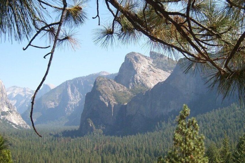 A mountainous landscape with dense forest and prominent rocky peaks. 3