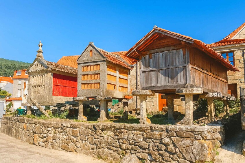A row of traditional stone buildings with red and wooden facades, set against a clear blue sky. 2