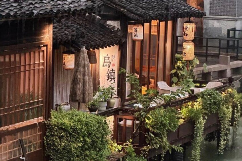 A traditional Chinese building with a tiled roof, wooden doors, and a sign with Chinese characters. 1