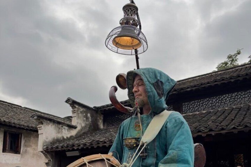 A person in a blue costume playing a traditional drum. 5