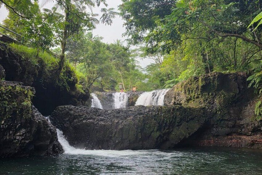 A waterfall cascading over rocks surrounded by lush greenery. 2