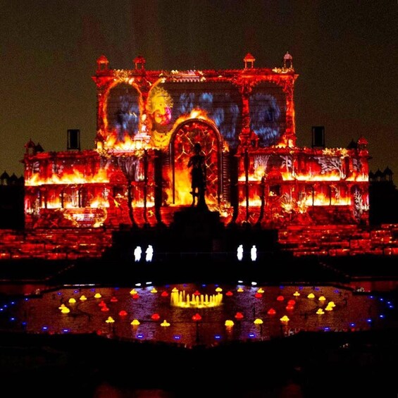 A brightly lit building with a central statue, surrounded by water and colorful lights. 5