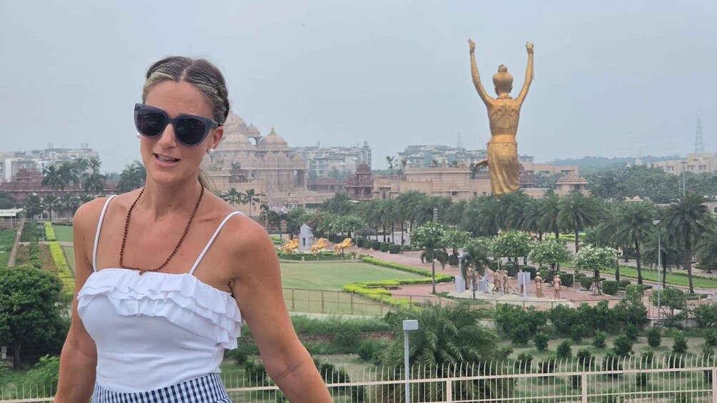A person standing with a view of a large golden statue and a temple in the background. 1